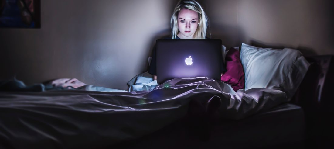 Young woman on her laptop while sitting in bed