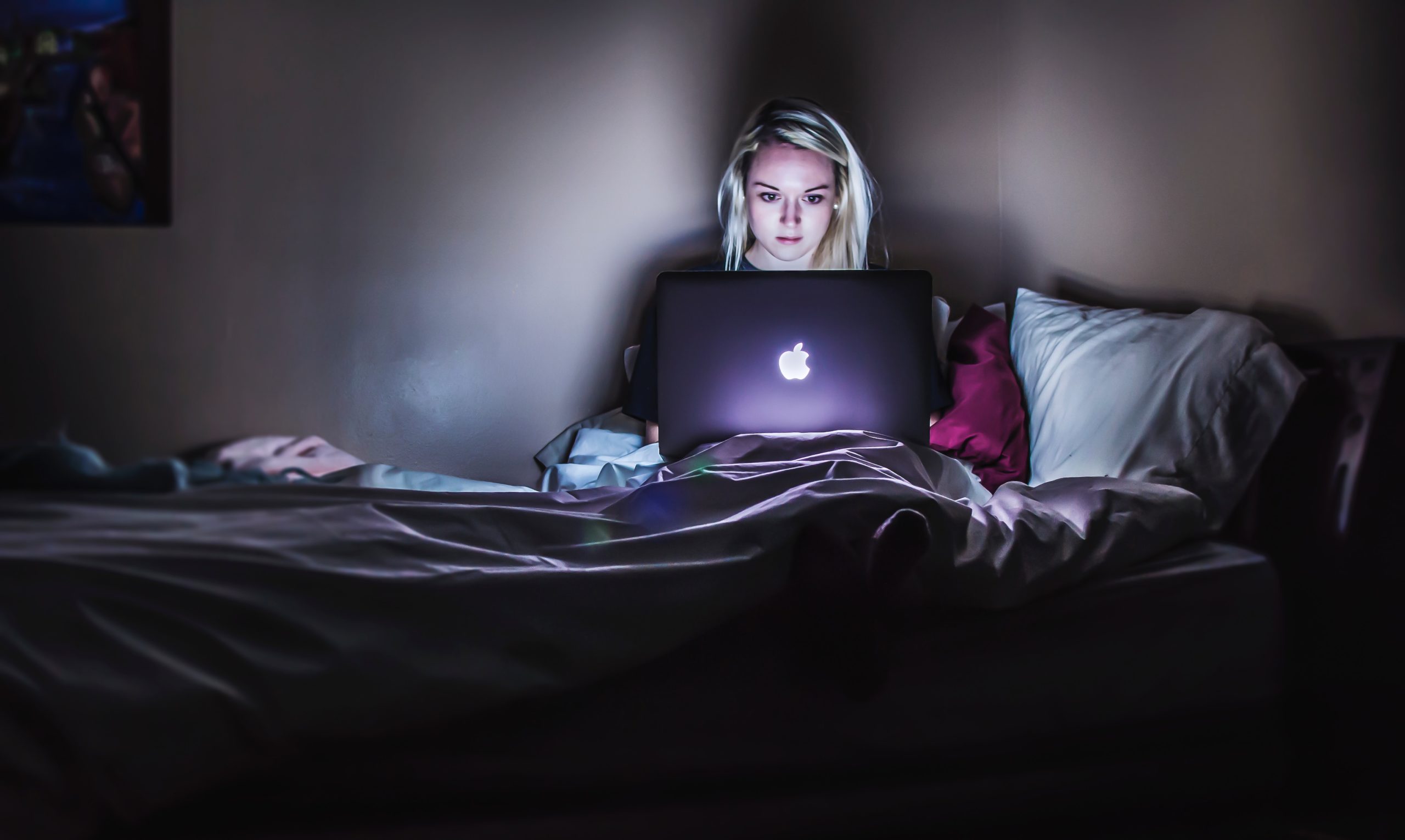 Young woman on her laptop while sitting in bed