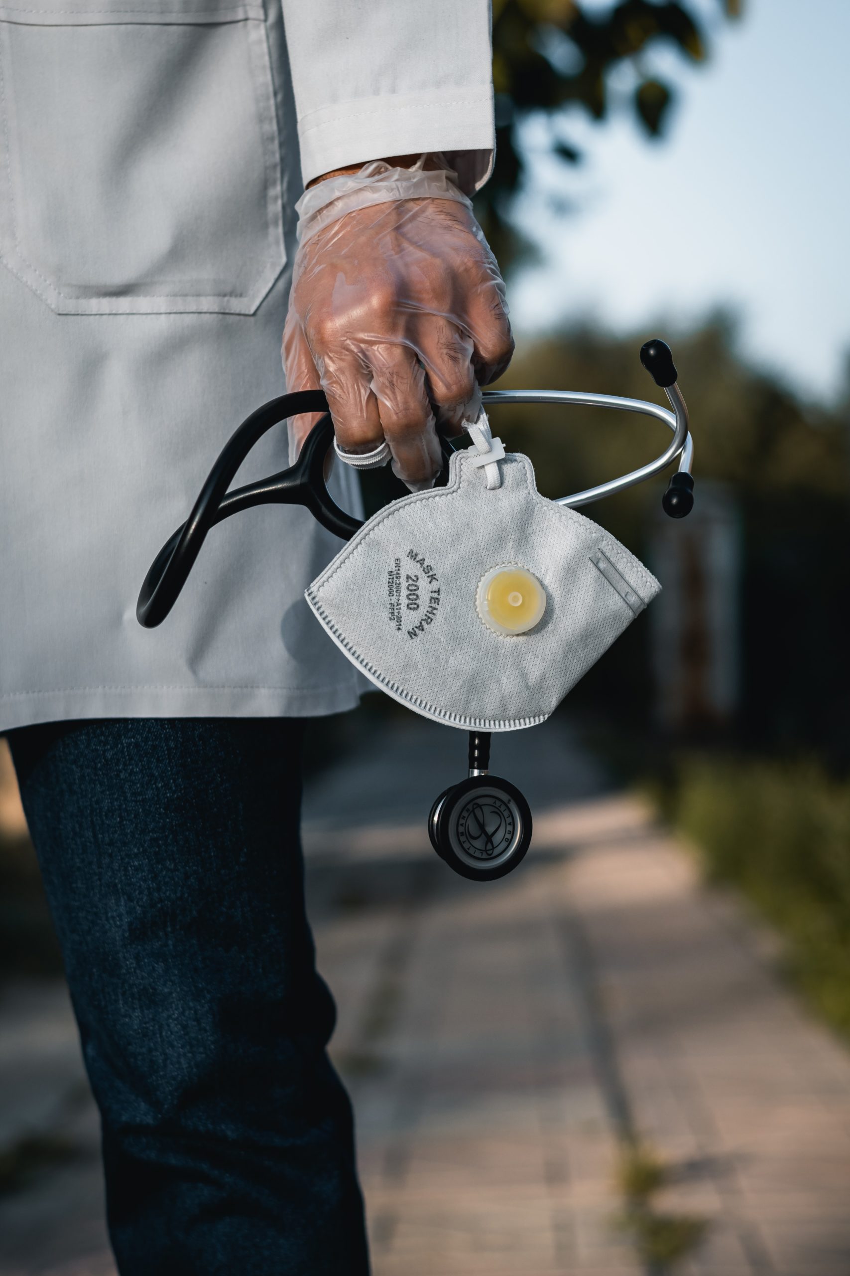 a person in a doctors coat, holding a face mask